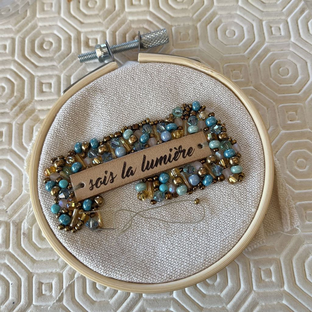 Broche en perles bleu turquoise au message en cuir gravé "Sois la lumière"