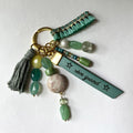 Bijou de sac vert et doré multi breloques en perles et message cuir gravé