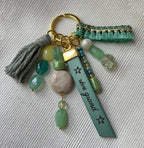 Bijou de sac vert et doré multi breloques en perles et message cuir gravé