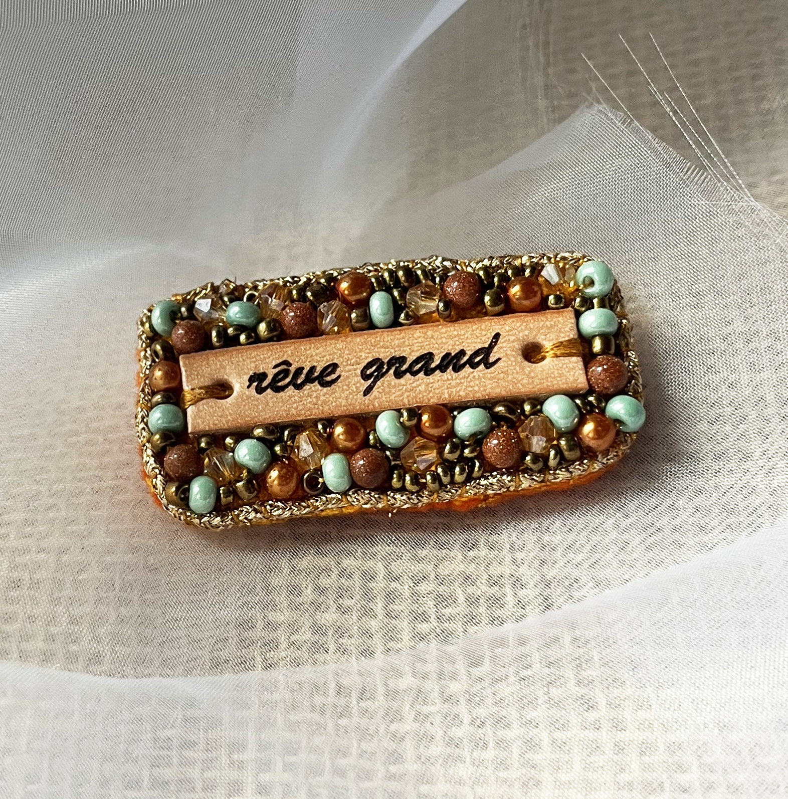Broche en perles dorées à message en cuir gravé "rêve grand"