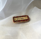 Broche à message en cuir gravé "sois béni" en perles rouges et dorées